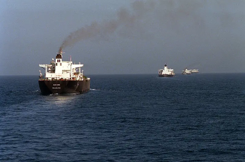 Color photo of a large tanker marked "Gas King, Philadelphia" leading a line of three more tankers across open water under a hazy sky.
