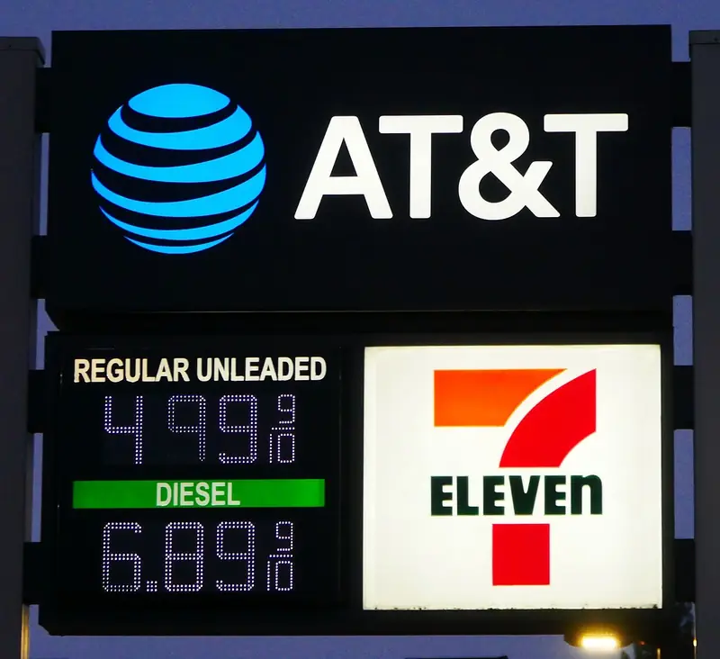 Lit price sign against a dark early-morning sky, showing regular unleaded at $4.99 and diesel at $6.89, under AT&T and 7-Eleven logos.